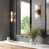 Gracy 2 Light Wall Sconce, Vintage Brass and real Alabaster stone wall sconces are shown in a primary bathroom flanking large black mirrors with dark grey stone tile backsplash.
