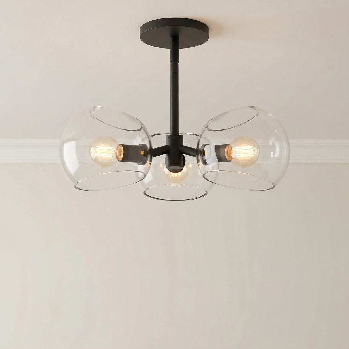 Flynn 3 Light Pendant 16", Matte Black with Clear Glass globe in a Modern Entryway with a simple light wall.