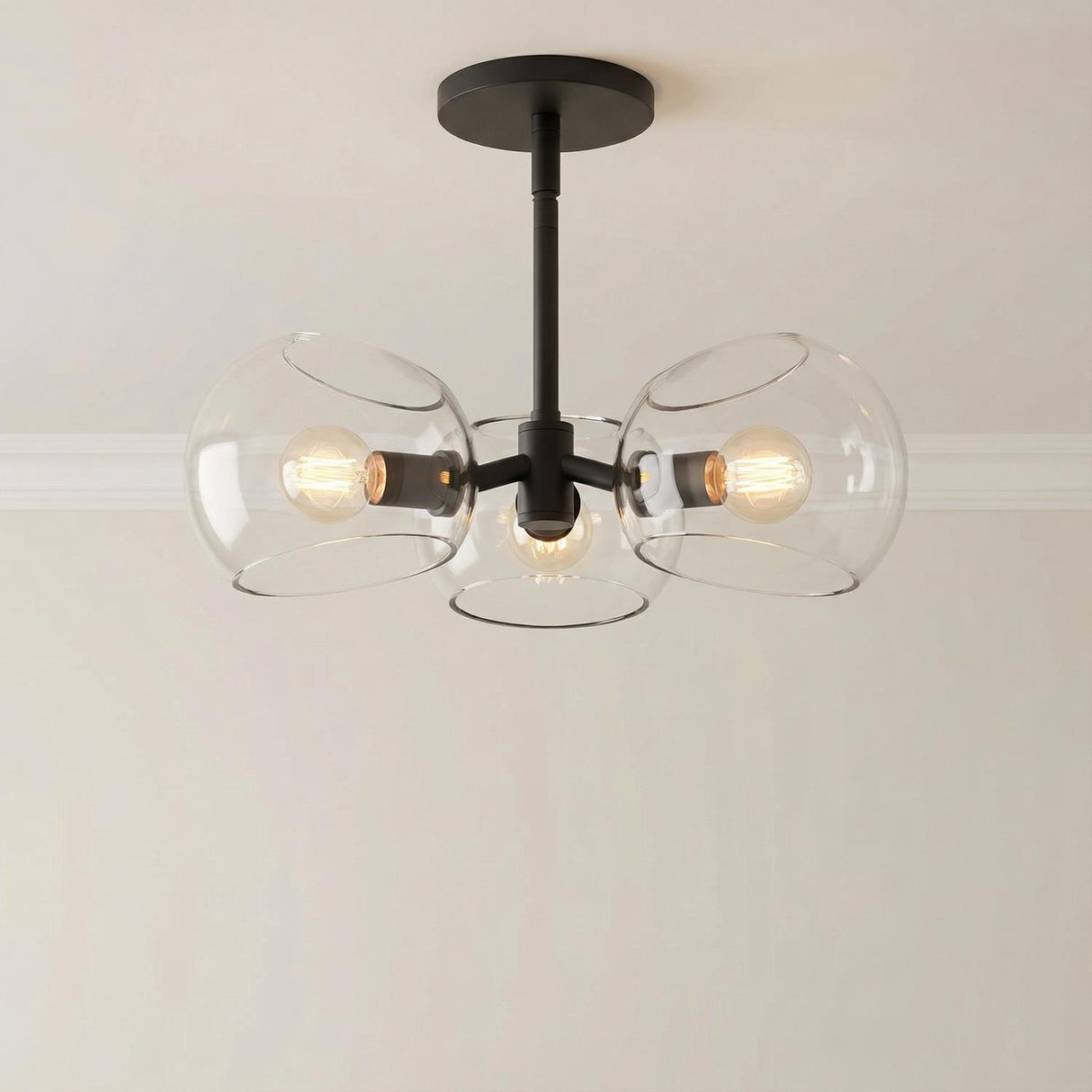 Flynn 3 Light Pendant 16", Matte Black with Clear Glass globe in a Modern Entryway with a simple light wall.