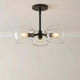 Flynn 3 Light Pendant 16", Matte Black with Clear Glass globe in a Modern Entryway with a simple light wall.