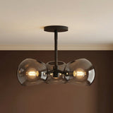 Matte Black 3-Light with Mirrored Smoke Glass globe pendant in a Modern Living Room with a neutral sofa.
