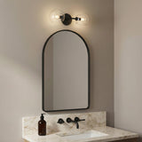 Flynn 2 Light Wall Sconce, Matte Black with Clear Glass styled in a Modern Bathroom with marble vanity.