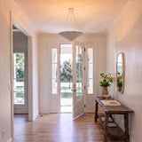 A modern farmhouse foyer with the Cora Pendant 30", Textured White centered over light hardwood floors, shiplap walls, and a rustic wood console table.