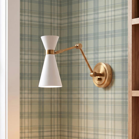 A mid-century office features the Aiden Articulating Wall Sconce, White and Antique Brass mounted on green plaid wallpaper beside natural oak shelving.