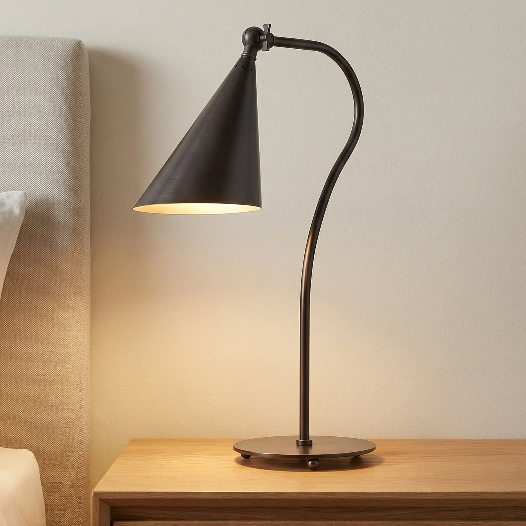 Faye Adjustable Table Lamp, Old Bronze geometric Table Lamp in a Modern Bedroom with a light wood nightstand and upholstered headboard.