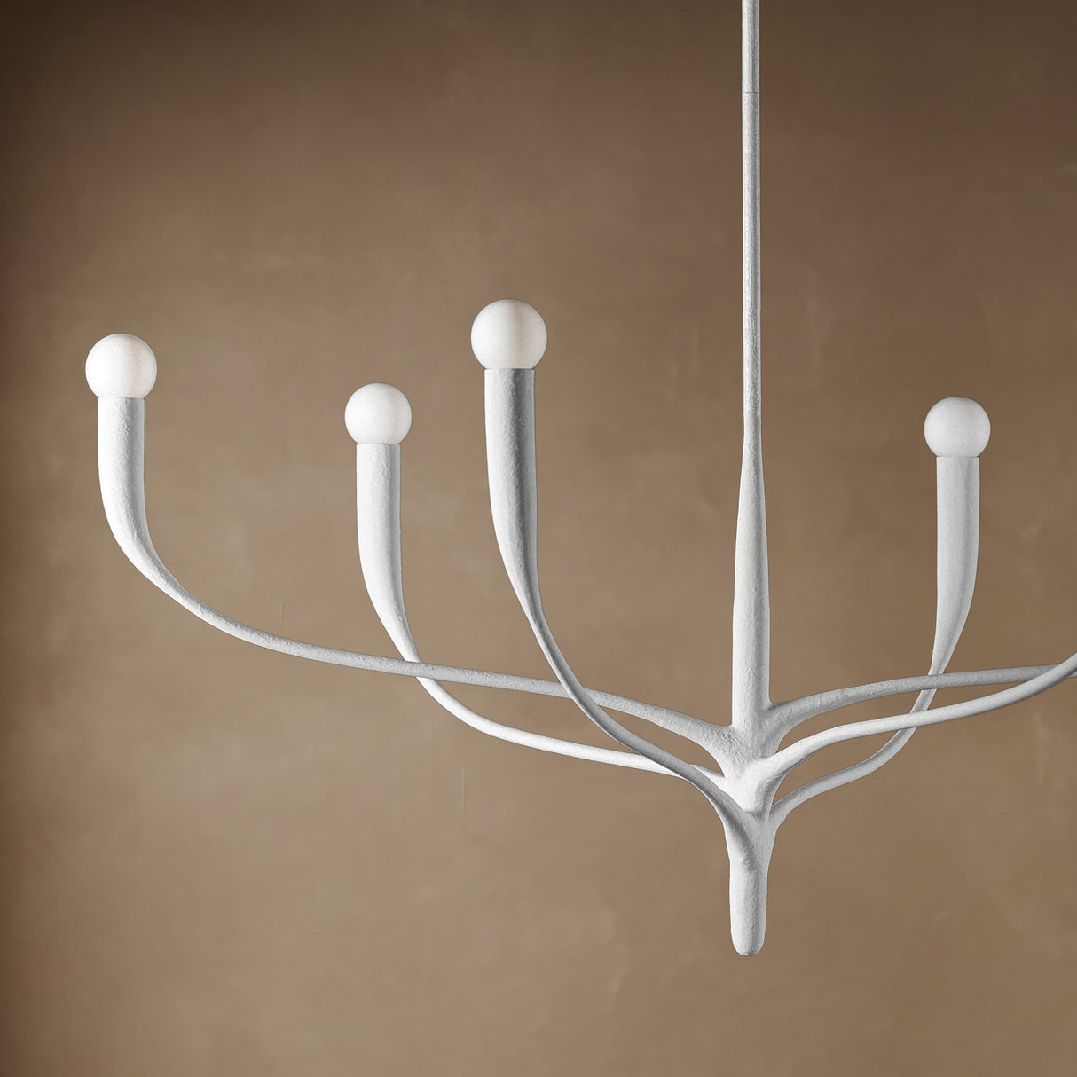 Close-up of Anita 6 Light Chandelier 37", White Plaster finish, on a textured brown backdrop.