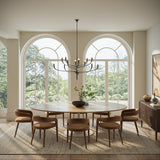 Anita 12 Light Chandelier is 52" wide and finished in Antique Iron shown in a grand dining room with a large oval table and arched windows.