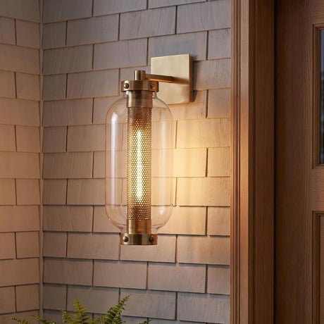 A coastal home exterior featuring the Bennett Outdoor Wall Light, Medium 19" Vintage Brass glowing on light gray shingle siding beside a natural wood door.