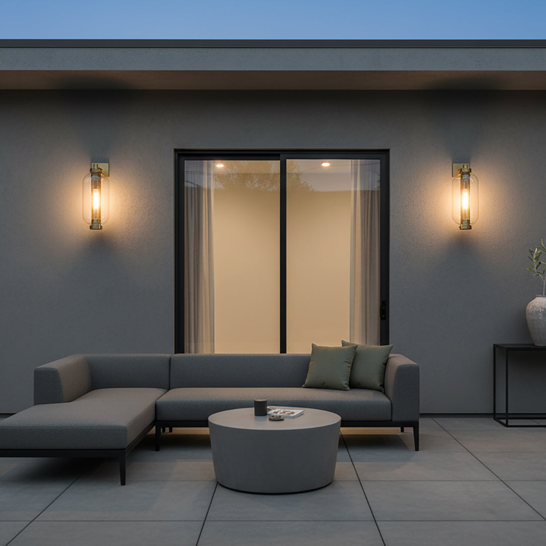 Bennett Outdoor Wall Light, Large 23" Vintage Brass - Two vintage brass wall lights illuminate a modern patio with a grey sectional sofa and a round coffee table.
