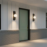 Gus Outdoor Wall Light, Large 24" Textured Black - Two globe MCM wall lights flanking a green front door on a ranch style home.