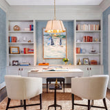A coastal office with the Avery 4 Light Large Pendant in aged brass and off-white linen over a white desk, featuring blue grasscloth and built-in shelving.