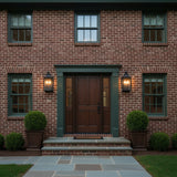 Bedford Outdoor Wall Light, Medium 21" Antique Black Iron - Two black lanterns illuminate the front door of a red brick house.