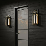 Dark walls and wooden door with glass panels flanked by two Waverly LED Outdoor Wall Lights, Small 18" in Black with Vintage Brass Accents.