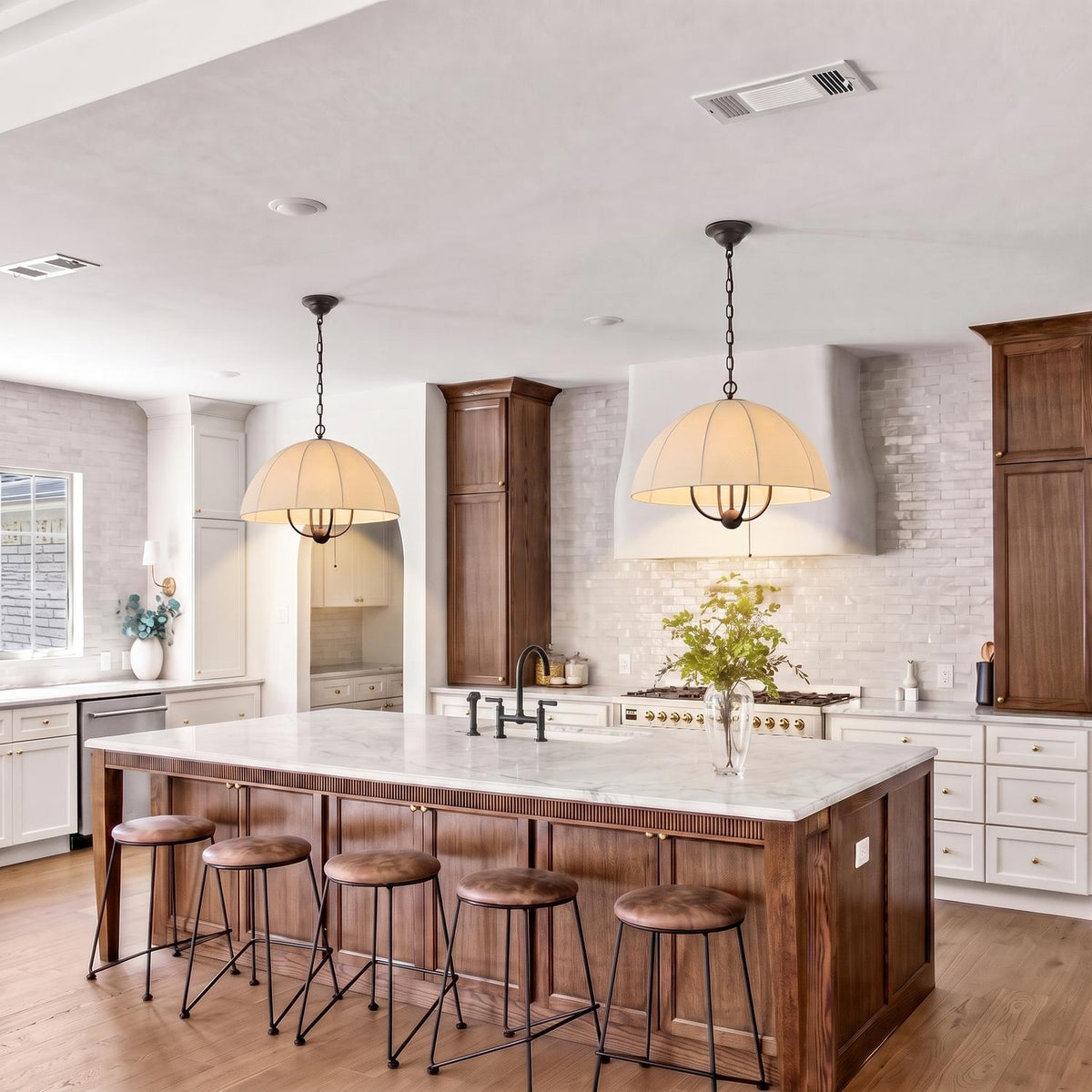 A modern farmhouse kitchen with two Trudy 4 Light Large Pendants in matte black with fabric shades over a marble wood island and white tile backsplash.