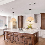 A modern farmhouse kitchen with two Trudy 4 Light Large Pendants in matte black with fabric shades over a marble wood island and white tile backsplash.
