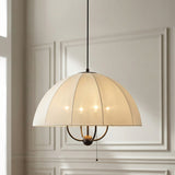 Trudy 4 Light Large Pendant 24", Matte Bronze with Cream Fabric Shade scalloped Pendant in a Transitional Living Room with white wall paneling.