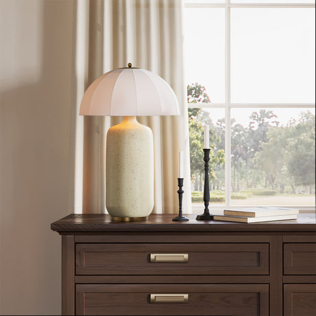 Trudy Table Lamp, Cream with Brass Accents on a wooden dresser with a window in the background
