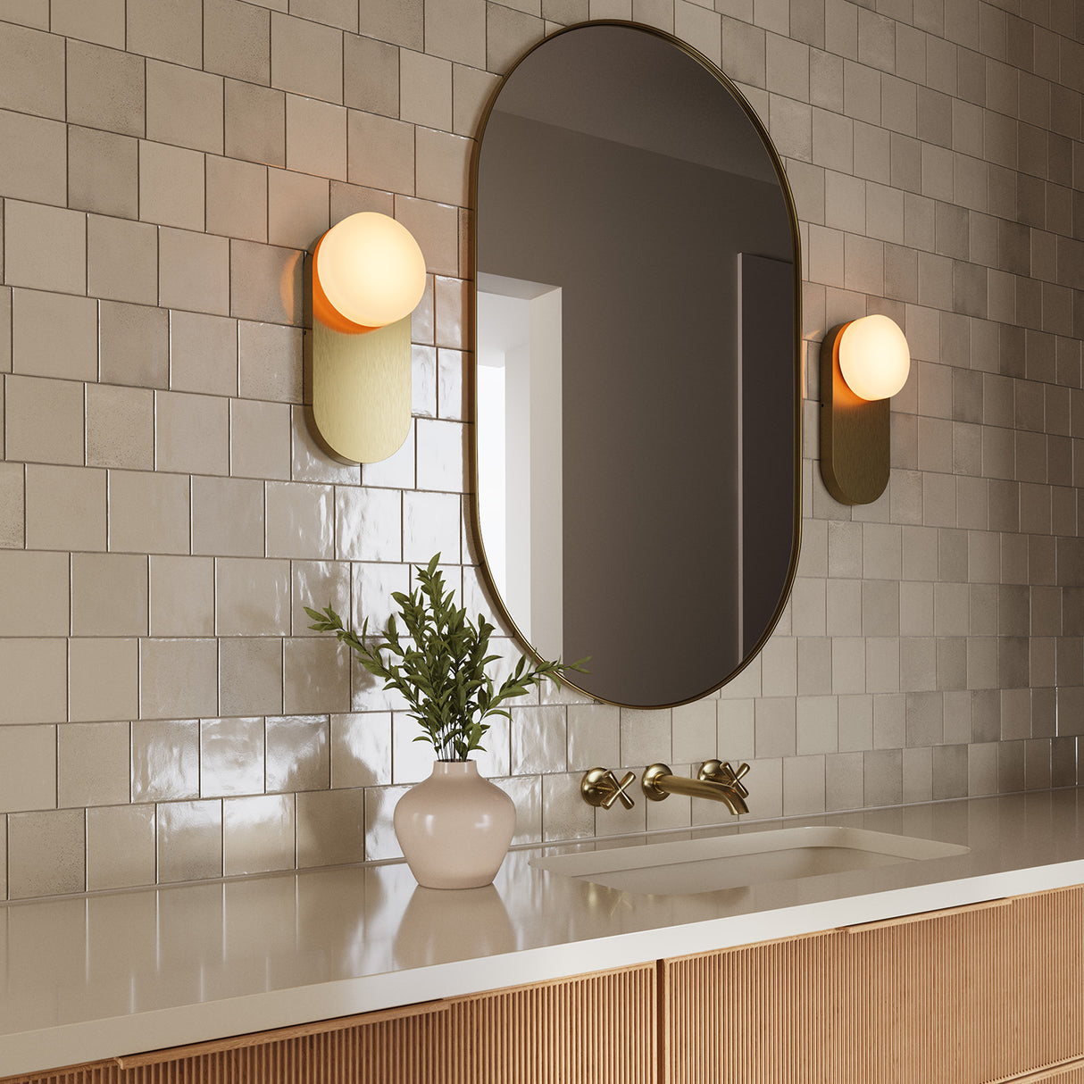 Two Enzo 13" Wall Sconces in Brushed Brass and Opal Glass, flanking a modern oval vanity mirror on handcrafted subway tile wall