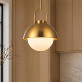 A contemporary kitchen featuring the Solene Pendant 16", Antique Brass and Opal Glass suspended beside fluted wood wall paneling, light wood cabinets, and marble backsplash.