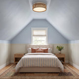 A coastal bedroom with the Amaris LED Flush Mount in cane and matte black on a sloped blue ceiling above a striped bed and white wainscoting.