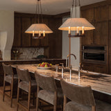A traditional kitchen with two Dawson Pendant 25", Bronze with Linen Shade fixtures over a white marble island with dark wood cabinets and a stone backsplash.