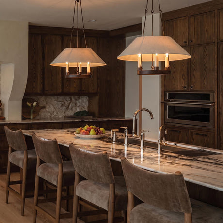A traditional kitchen with two Dawson Pendant 25", Bronze with Linen Shade fixtures over a white marble island with dark wood cabinets and a stone backsplash.
