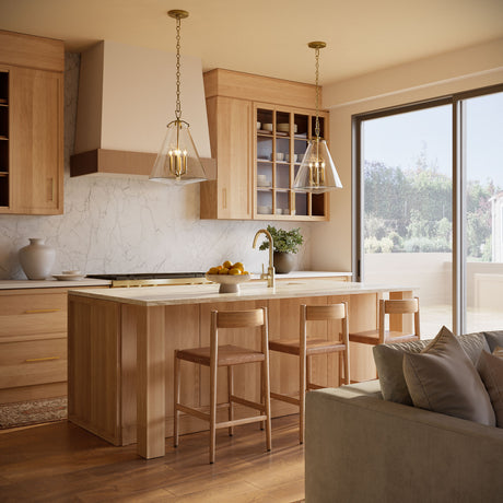 Two Addison Extra Large Pendant lights in Brass and clear glass, shown above a kitchen island in a warm oak wood modern kitchen.