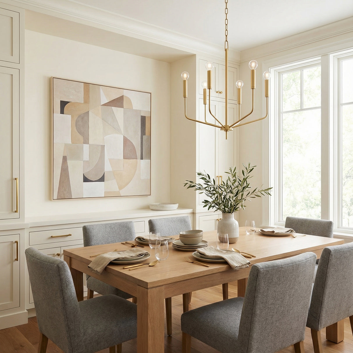 Hollis 6 Light Chandelier 24", Aged Brass geometric chandelier in a Transitional Dining Room with a light wood dining table and grey upholstered chairs.