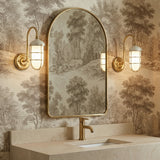 Sawyer Wall Sconce 13", Aged Brass and Off White for shown in a bathroom with art wall paper and an arched mirror