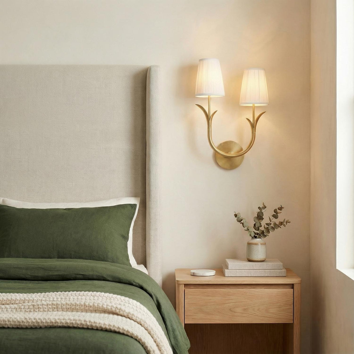 Aged Brass leaf design wall sconce in a Transitional Bedroom with an upholstered bed and olive green bedding.