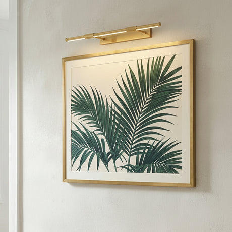 Ethan Extra Large LED Picture Light, Aged Brass linear Picture Light in a Modern Living Room with framed palm leaf artwork.