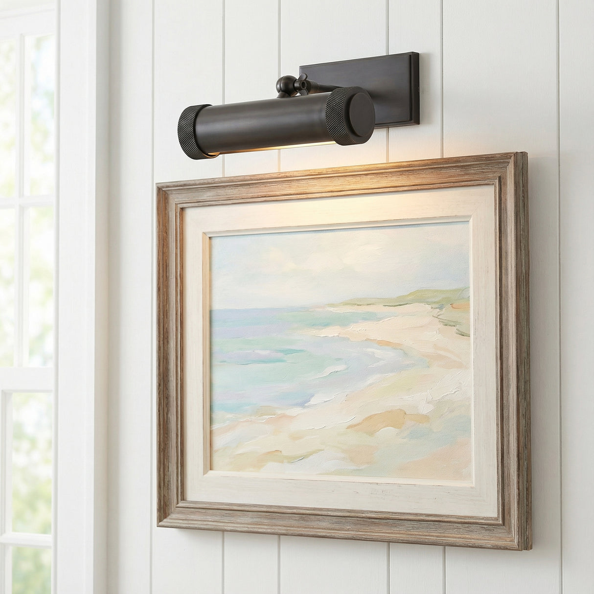 Graham Small Picture Light, Distressed Bronze geometric Wall Sconce in a Coastal Living Room with white shiplap walls and a framed beach painting.