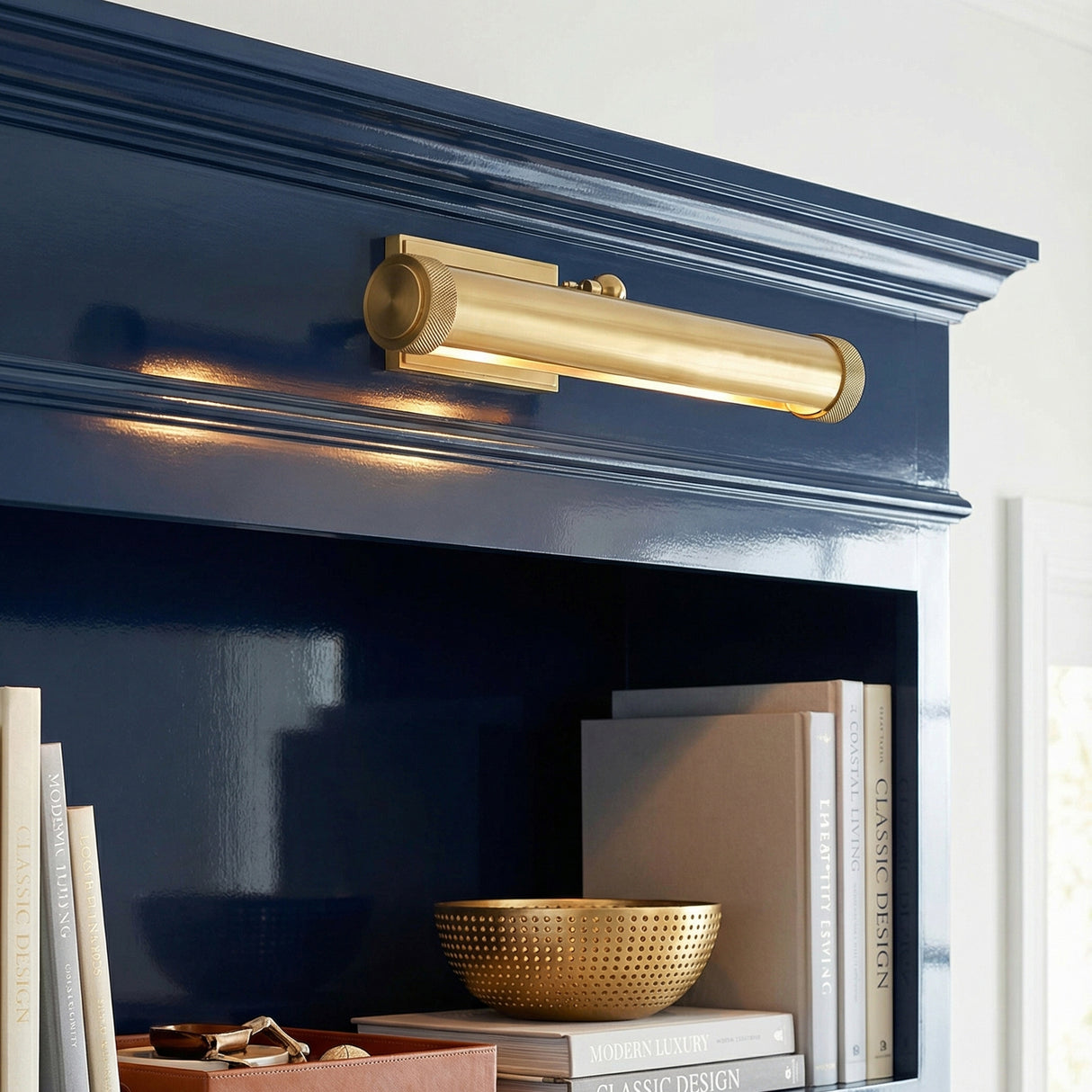Graham Medium Picture Light, Aged Brass linear Picture Light in a Transitional Living Room with deep blue built-in shelves.