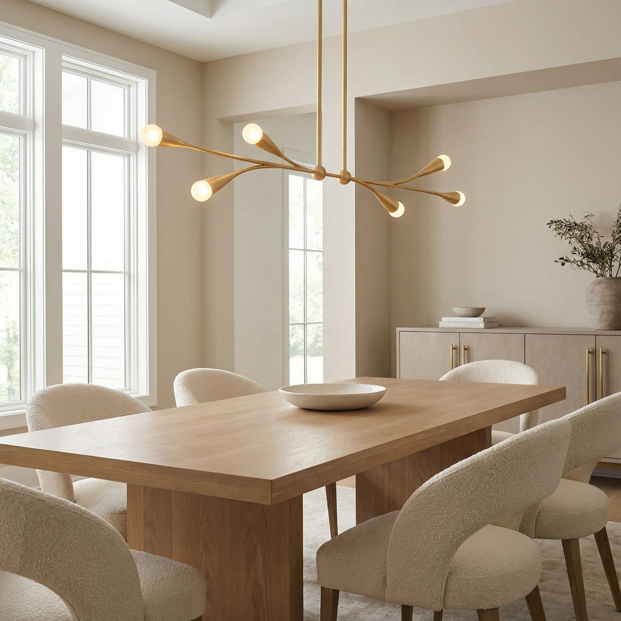 Flora 6 Light Linear Chandelier 50", Gold Leaf linear Chandelier in a Modern Dining Room with a light oak table and boucle chairs.