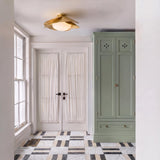 A transitional foyer with a gold leaf and milk glass flush mount along the ceiling above patterned marble floor tiles and a sage green armoire.