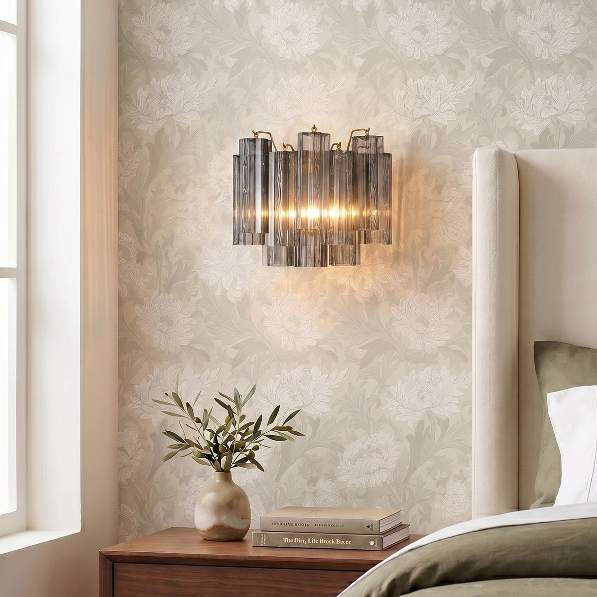 Smoke Glass geometric Wall Sconce in a Transitional Bedroom with floral wallpaper and a beige wingback headboard.