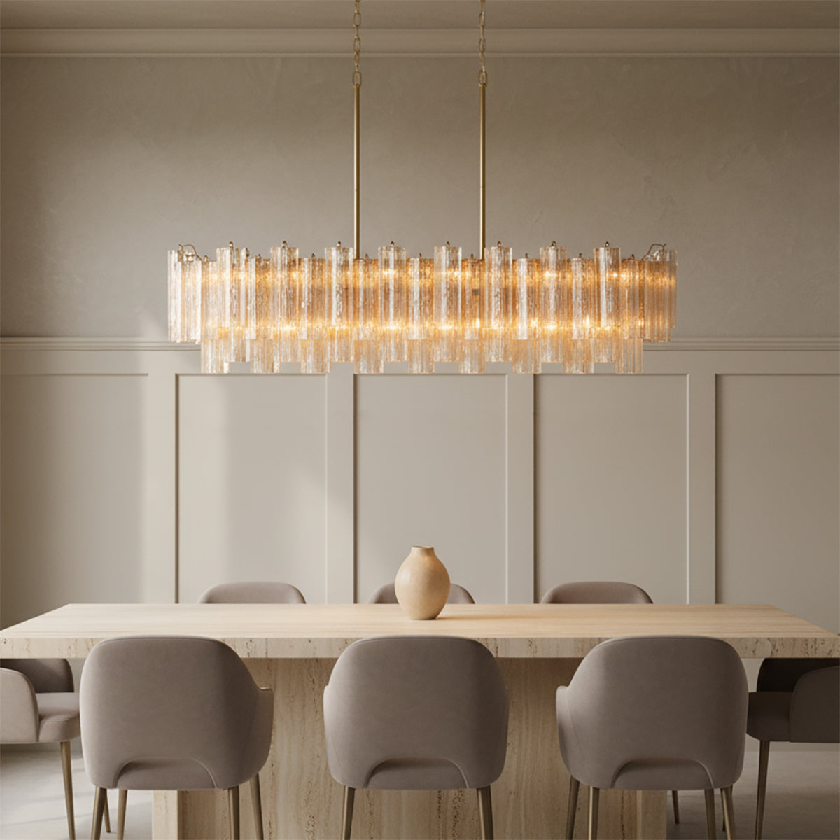 Grace Linear Chandelier 52, Brass with Topaz Glass - A long chandelier hangs over a dining table in a neutral-toned dining room.