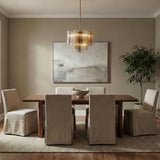 Grace Brass geometric tiered Chandelier in a Contemporary Dining Room with a wooden table and slipcovered chairs.