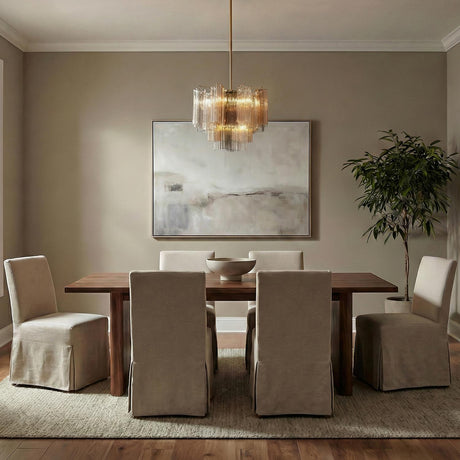 Grace Brass geometric tiered Chandelier in a Contemporary Dining Room with a wooden table and slipcovered chairs.