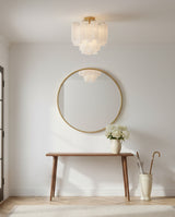 Grace Semi-Flush 18, Brass with White Glass - A brass semi-flush mount light with white glass shades hangs above a wooden console table with a round gold mirror and a vase of white flowers.