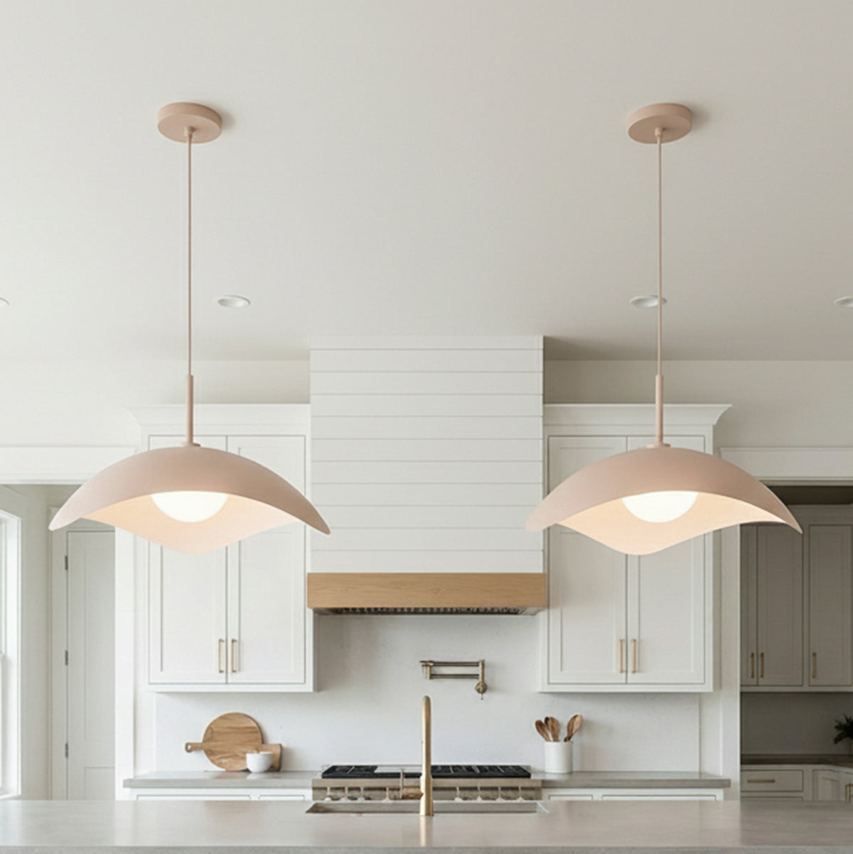 A contemporary kitchen with two Presley Pendant 22", Blush pendants featuring a blush finish and frosted glass globes over the island with white shaker cabinetry.