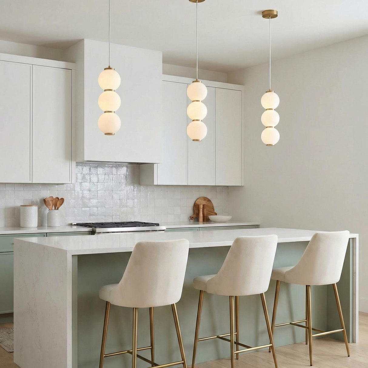 Shai LED Pendant 7", Aged Brass and Opal Glass globe Pendant in a Modern Kitchen with a white marble island and velvet stools.