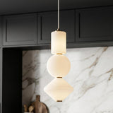A contemporary kitchen with a Shai LED Pendant 8" in aged brass and opal glass over the island with a white marble backsplash and dark cabinets.