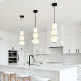 A minimalist white kitchen features three Shai LED Pendant matte black and opal glass pendants over the island with flat-panel white cabinets and a matte black faucet.