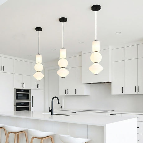 A minimalist white kitchen features three Shai LED Pendant matte black and opal glass pendants over the island with flat-panel white cabinets and a matte black faucet.