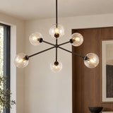 A mid-century living room with the Gurt 6 Light Chandelier 40", Matte Black featuring clear glass globes suspended before rich wood wall paneling.