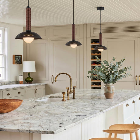 A modern farmhouse kitchen featuring three matte black and walnut Sheila LED Pendants over a white marble island with beige cabinetry and a brass bridge faucet.
