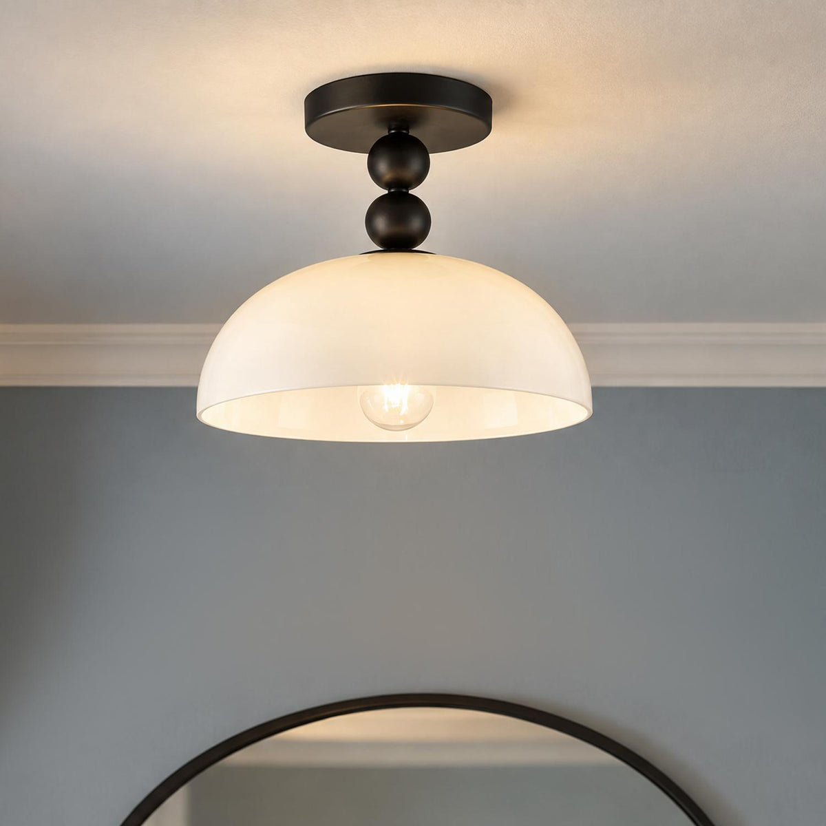 A transitional foyer features an Archie Flush Mount 12" in matte black with an opal glass shade installed above a round dark-framed mirror.