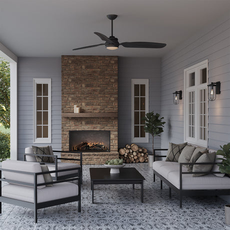 Hobbs 60" ceiling fan in matte black, shown in an outdoor living room with cool grey walls and a pattern tied floor. Two Orson Outdoor Wall Lights are flanking a white window on the back wall.