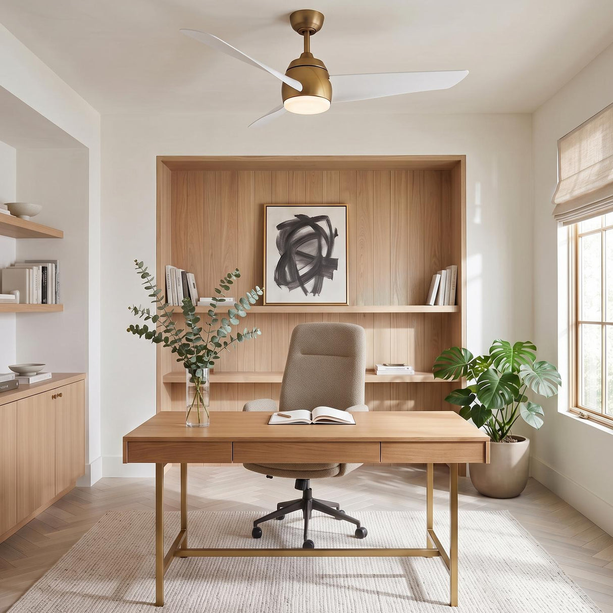 A modern office with the Lorain LED Ceiling Fan 54" in brushed brass and white mounted over a light wood desk and built-in shelving.